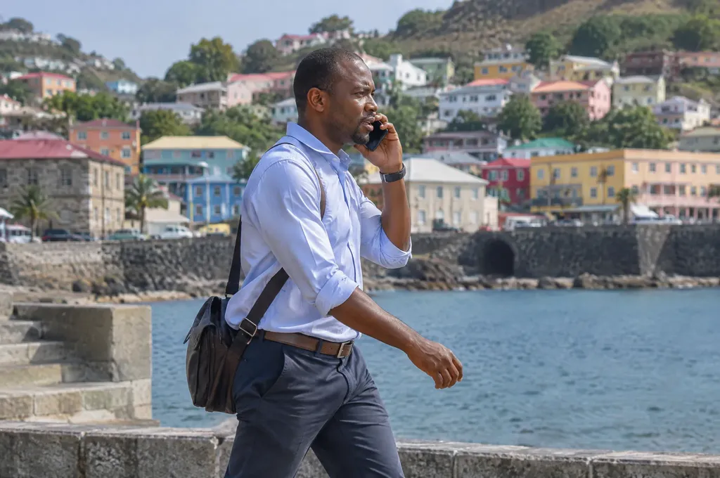 Businessman on a phone call walking by the harbour in St George's, Grenada