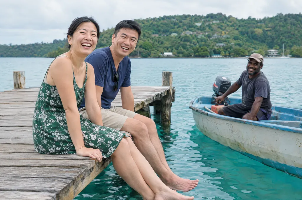 Couple sitting on a jetty in Port Vila, Vanuatu, with a local boatman nearby