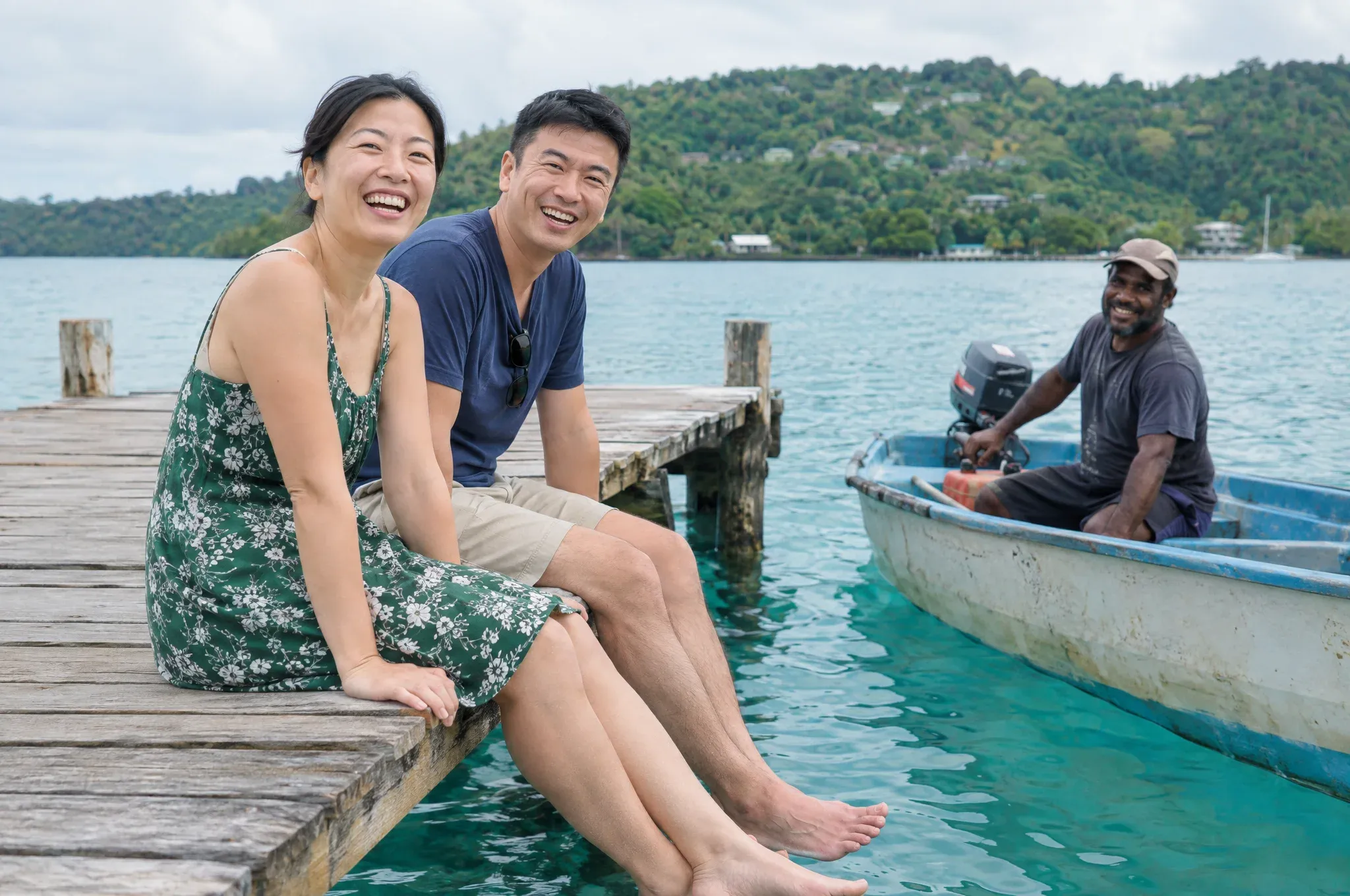 Couple sitting on a jetty in Port Vila, Vanuatu, with a local boatman nearby